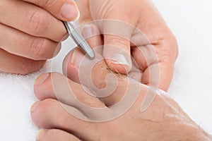 Manicurist removing cuticle from the nail photo