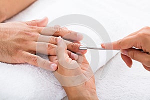 Manicurist Removing Cuticle From Person`s Nail photo