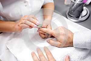 Manicurist rounding the edges using nail file