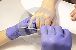 Manicurist shapes, files beautiful woman& x27;s nails, holding finger. Caucasian manicure photo