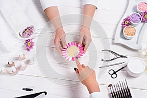 manicurist showing samples of nail varnishes to woman