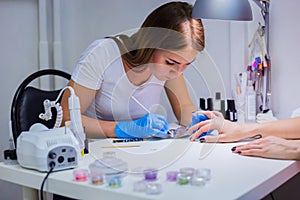 Manicurist treating client at beauty salon - painting on the nail