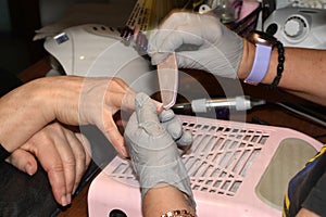 A manicurist uses a nail file to straighten his nails.