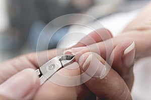 A manicurist uses a pair of nippers to remove a hangnail from the edge of a index fingernail or perionychium. photo