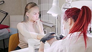 Manicurist woman in gloves in the beauty salon processes the cuticle on the nails of the client