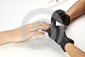 manicurist during work using nail metal stick. a man manicure process. an unrecognizable caucasian person making nail