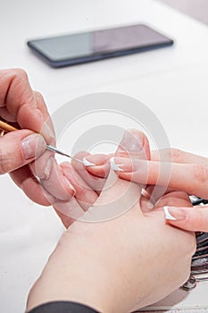 manicurist working on the nails of a female client, tidying up the manicure and putting the health of the nails in order, close-up