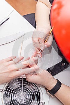 manicurist working on the nails of a female client, tidying up the manicure and putting the health of the nails in order, close-up