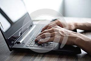 Male hands typing on black laptop computer keyboard photo