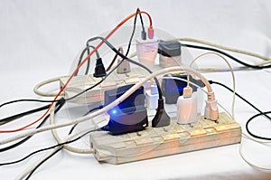 Many electrical cords connected to a single power strip or extension block.