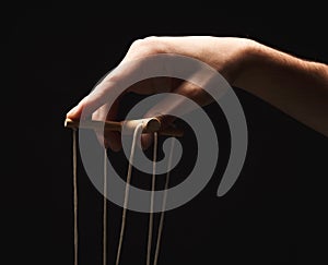 Manipulators hand with marionette string isolated on black