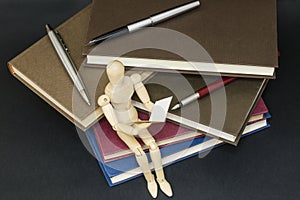 Maniqui reading sitting on a mountain of books and pens photo