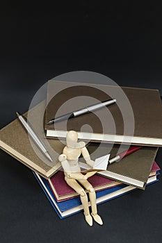 Maniqui reading sitting on a mountain of books and pens photo