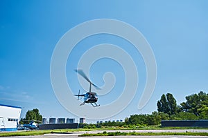 Manned helicopter overflying helipad on clear day