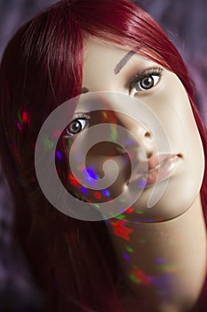 Mannequin with colorful stars on her face posing against a blurry background