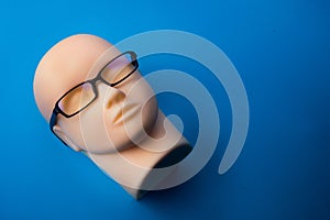 Mannequin head with black eyeglasses on background
