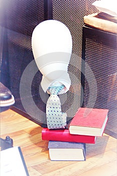 Mannequin head on a stand with a tie and books in a shop window