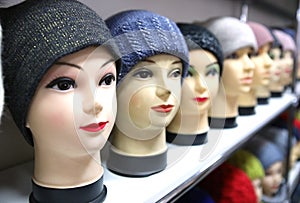 Mannequin heads in knitted hats and scarves. Mannequins female heads in hats and scarfs close up. Woolen knitted caps