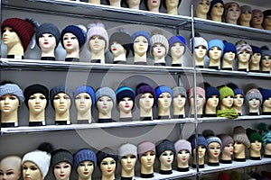 Mannequin heads in knitted hats and scarves. Mannequins female heads in hats and scarfs close up. Woolen knitted caps