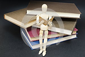 Mannequin sitting on a mountain of reading books