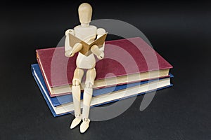 Mannequin sitting on two books reading photo