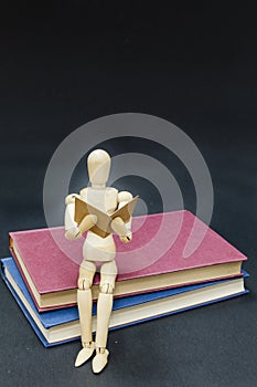 Mannequin sitting on two books reading