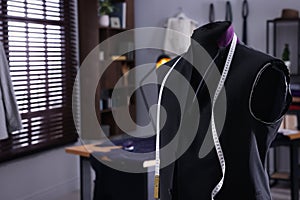 Mannequin with unfinished suit jacket and measuring tape in tailor shop, space for text