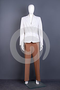 Mannequin in white blazer and brown trousers.