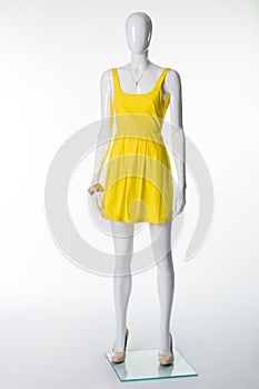 Mannequin in a yellow summer dress and beige shoes with heels.