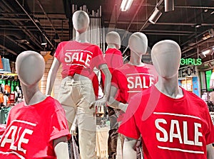 Mannequins in red T-shirts in a shop window. Sale. Advertising