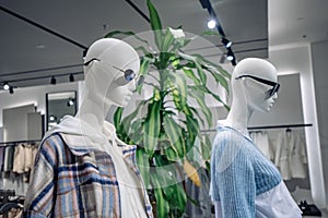 Mannequins in stylish clothes and trendy sunglasses in the window of a fashion store