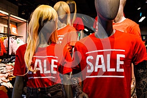 Mannequins in a window of a clothing store in T-Shirts With Signs Advertising Sale