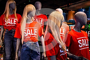 Mannequins in a window of a clothing store in T-Shirts With Signs Advertising Sale