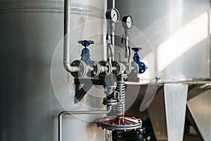 Manometers, pressure gauges and iron pipes on steel tanks at food or beverage factory, close up