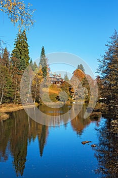 Manor house by the river in autumn landscape