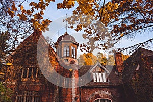 Manor house with trees in autumn colors and fall trees. Old Victorian Haunted House with ghosts. Abandoned house in autumn wood