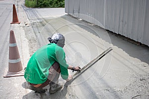 Manpower spreading poured concrete on the road.