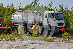 Mans with briefcase in protective hazmat suit, tank