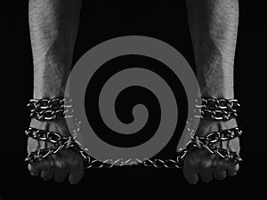 Mans hand entangled with a metal chain, concept slavery, hostage and freedom.Black and white photo