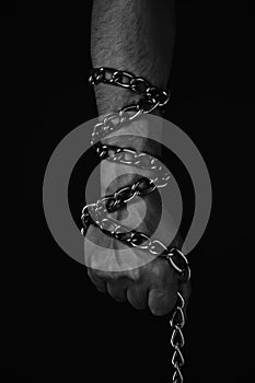 Mans hand entangled with a metal chain, concept slavery, hostage and freedom.Black and white photo