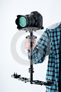 Mans hand holding camera stabiliser with digital camera on top.