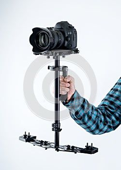 Mans hand holding camera stabiliser with digital camera on top.