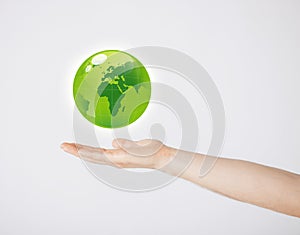 Mans hand holding green globe