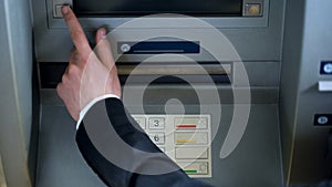 Mans hand pressing button on display screen of ATM machine, bank account access
