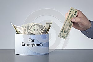 Mans hand puts of dollars in box for emergency.