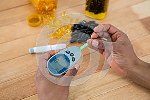 Mans hand testing blood sugar with glucometer