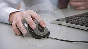 Mans hand using a computer mouse. Businessman in a white shirt uses a computer mouse. Close up