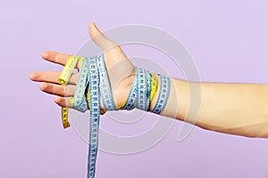 Mans hand wrapped with blue and yellow measuring tapes
