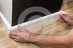 Mans hands fitting skirting board