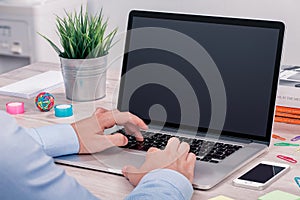 Mans hands keyboarding on macbook laptop with blank screen mockup